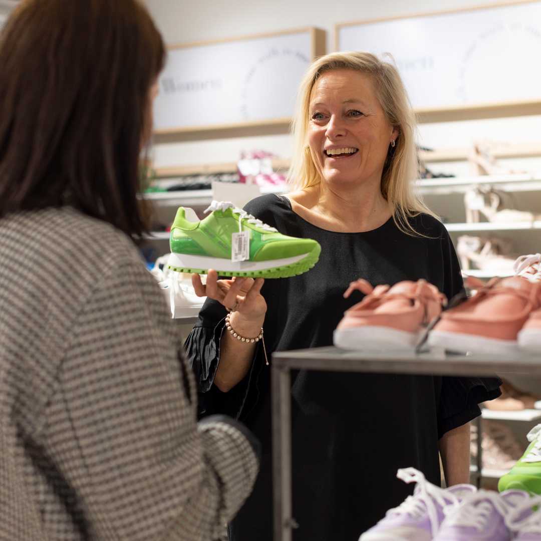 Medarbejder fra Skoringen på Amager, viser et par grønne sneakers til en kunde. 